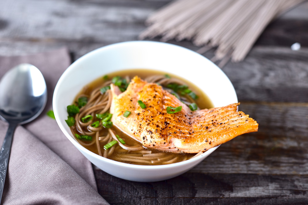Кладем в каждую тарелку по куску лосося для легкого супа в азиатском стиле с гречневой лапшой и лососем