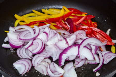 Put sliced onion and pepper in the large frying pan for pork with a sweet pepper