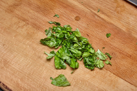 Chop a few basil leaves for pork with a sweet pepper