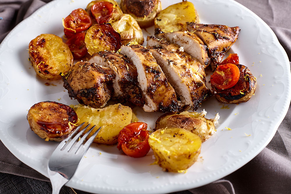 Serve gentle chicken breasts baked with vegetables in balsamic-honey marinade on the potatoes and cherry tomatoes 