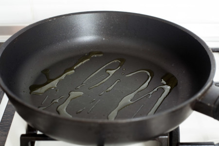 Добавляем оливковое масло в сковороду для куриных грудок с розмарином и шпинатом в конверте из фольги за 15 минут