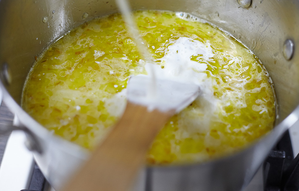 Добавляем бульон и сливки в кастрюлю для чесночного супа с миндалем и апельсином