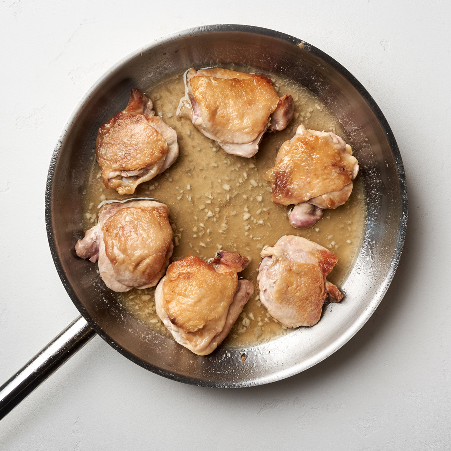 Карамельная курица по-вьетнамски. Шаг 4. Переверните куриные бедра, накройте крышкой и готовьте 15 минут, пока соус не приобретет красивый карамельный оттенок и не загустеет.