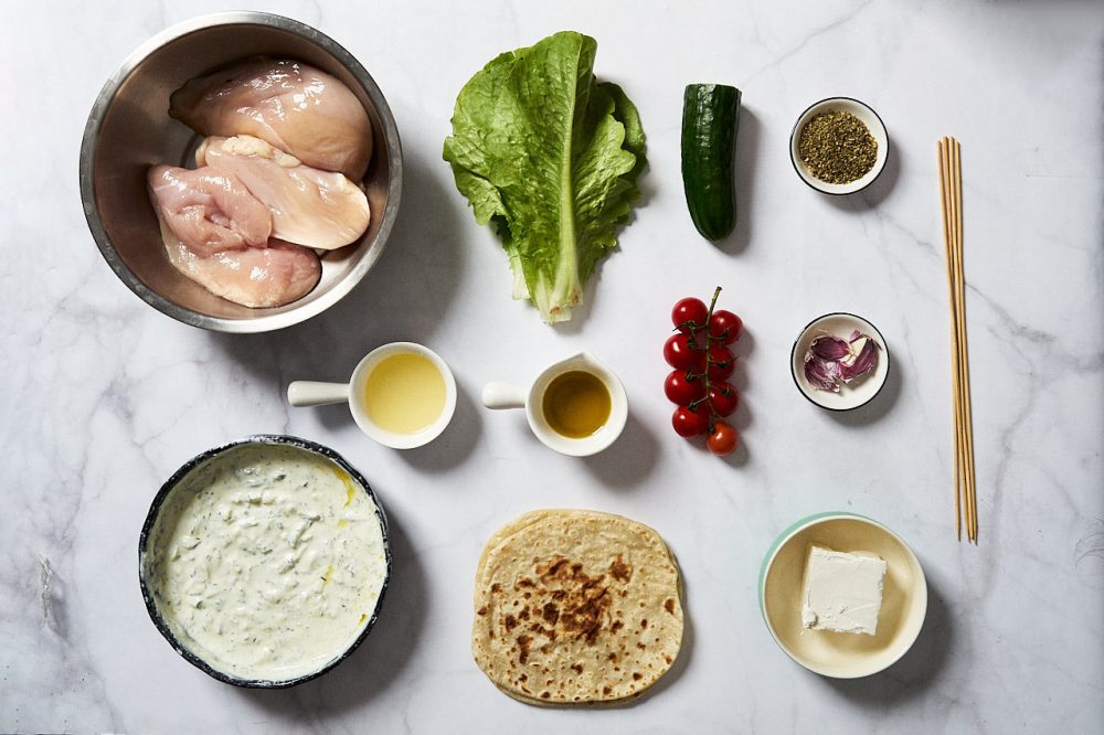 Ingredients for making pita with chicken souvlaki: chicken, Romaine lettuce, tzatziki sauce, cucumber, cherry tomatoes, oregano, garlic, feta, pita, lemon juice
