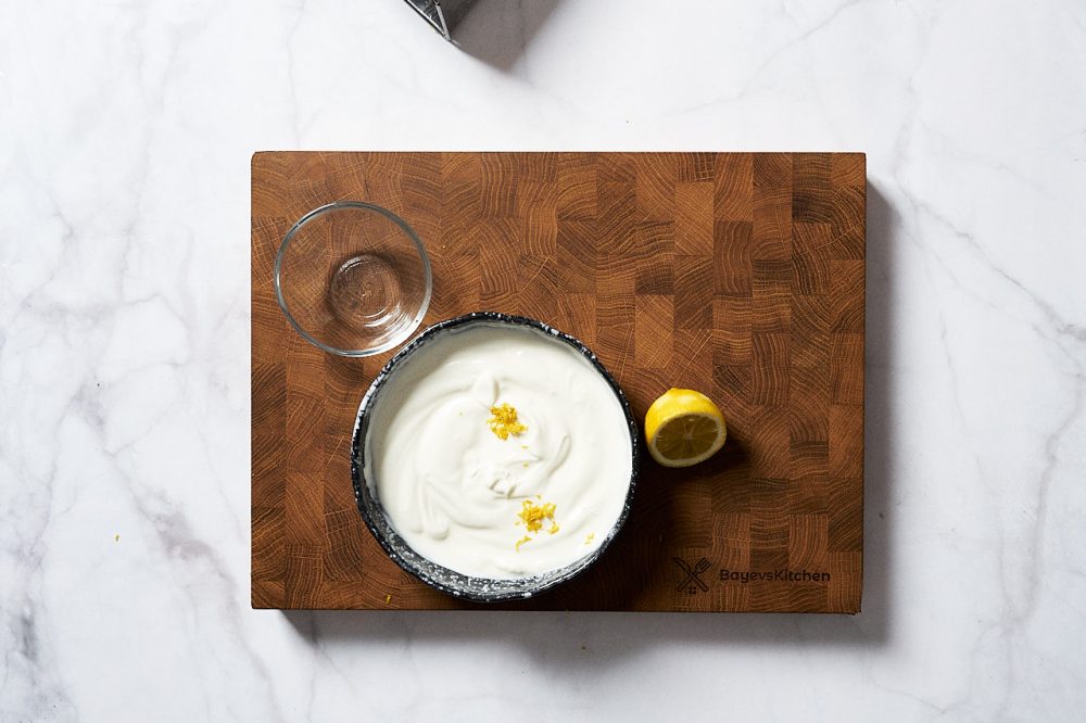 На дрібній тертці натріть цедру половини лимона, додайте в йогурт.
