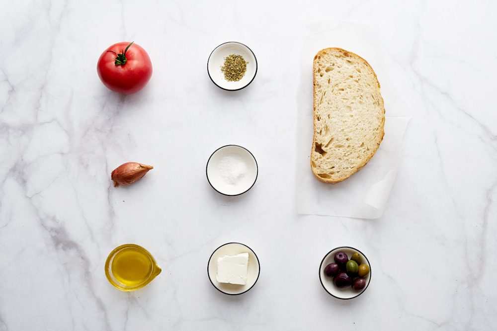 Ингредиенты для Критского Салата Дакос: помидоры лук шалит, оливковое масло, соль, оливки, орегано, хлеб, Фета