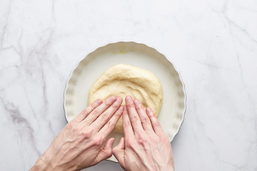 Положите тесто в форму и распределите руками по форме