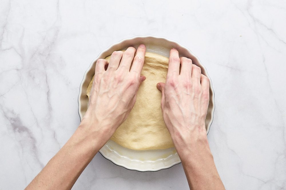 Положите тесто в форму и распределите руками по форме