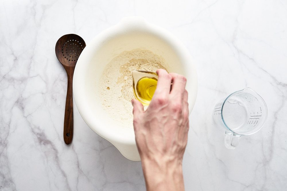 Влийте оливкову олію в борошно, замісіть тісто