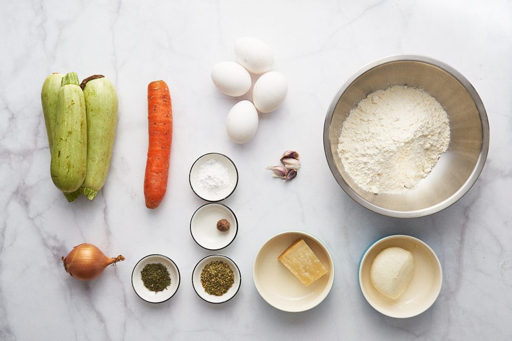 Ingredients for zucchini pie with cheese: zucchini, carrots, eggs, onions, thyme, oregano, nutmeg, garlic, Parmesan, flour, mozzarella