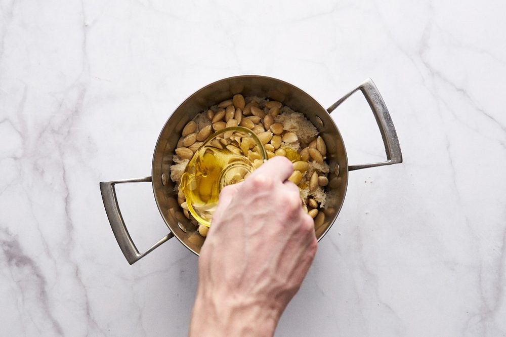 Додаємо оливкову олію до інгредієнтів у каструлі для супу Ajo Blanco