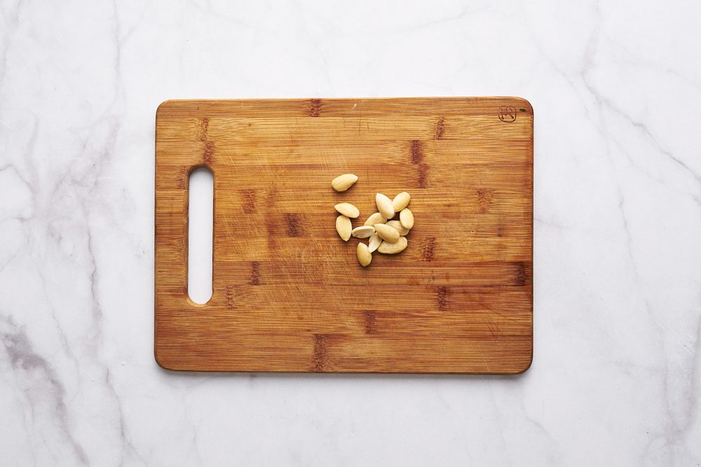 Handful of almond kernels on a wooden cutting board