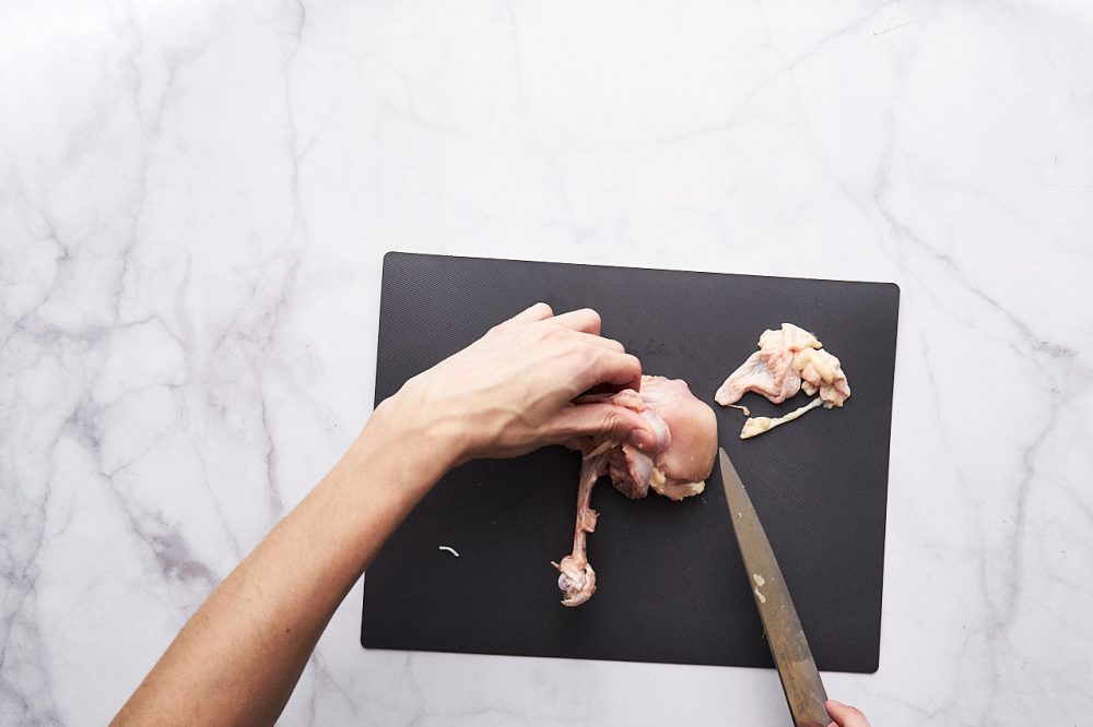 Срежьте ножом мясо курицы с кости для приготовления начинки самсы с курицей