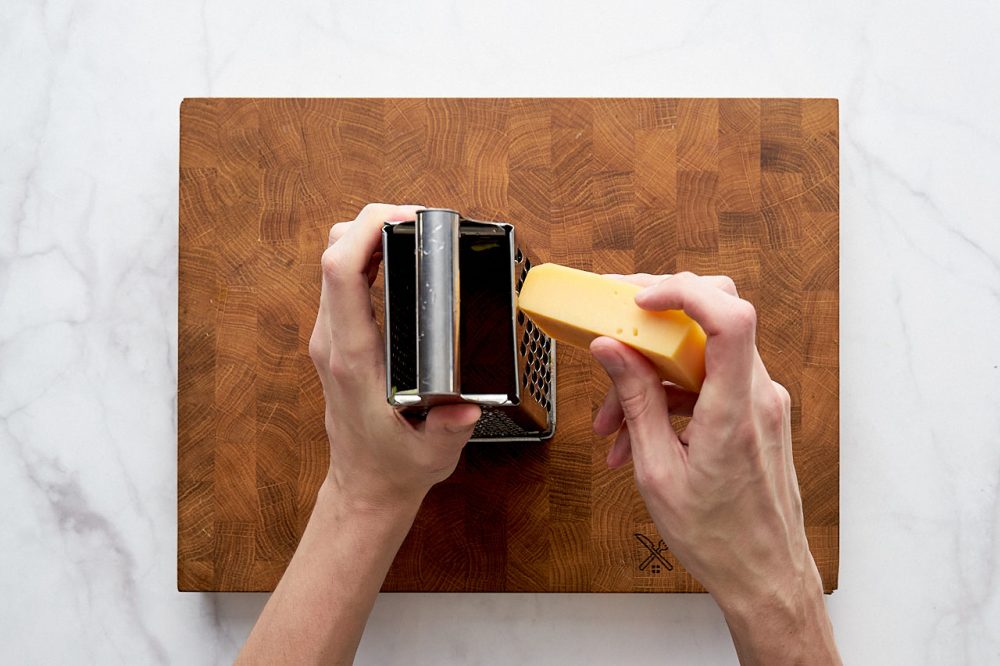 Натріть сир на терці для приготування цукіні з сиром в духовці