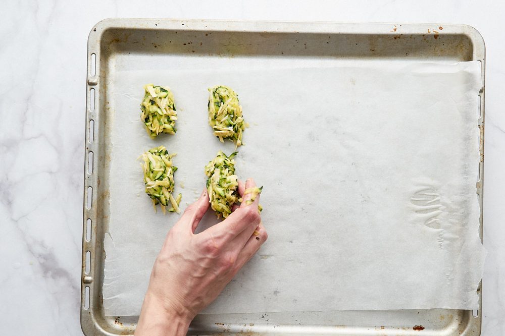 Formed zucchini patties with cheese on a baking tray
