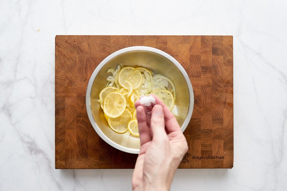 Посыпьте солью лук и лимон в миске