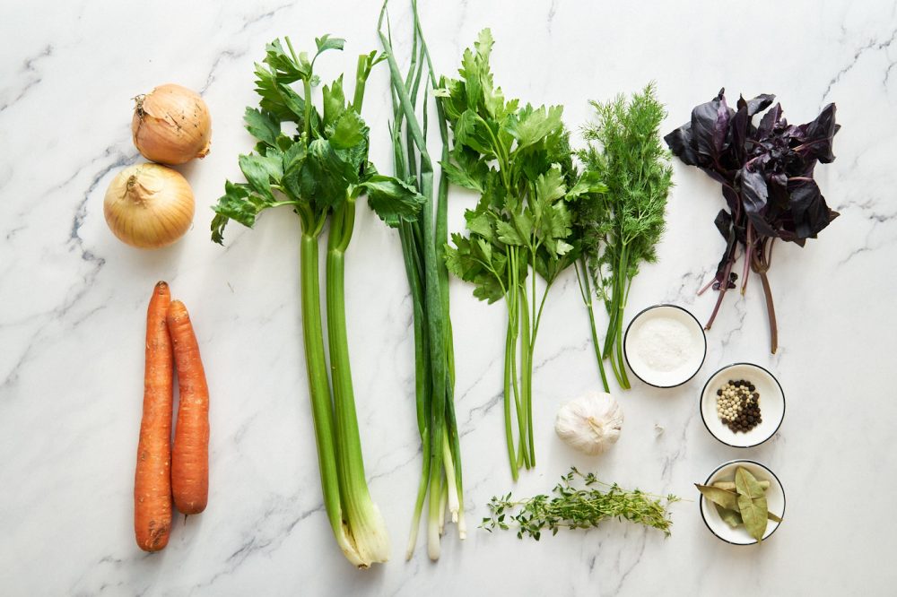 Ingredients for cooking Basic vegetable broth: carrots, celery stalks, onions, herbs, pepper, bay leaf, vegetable oil