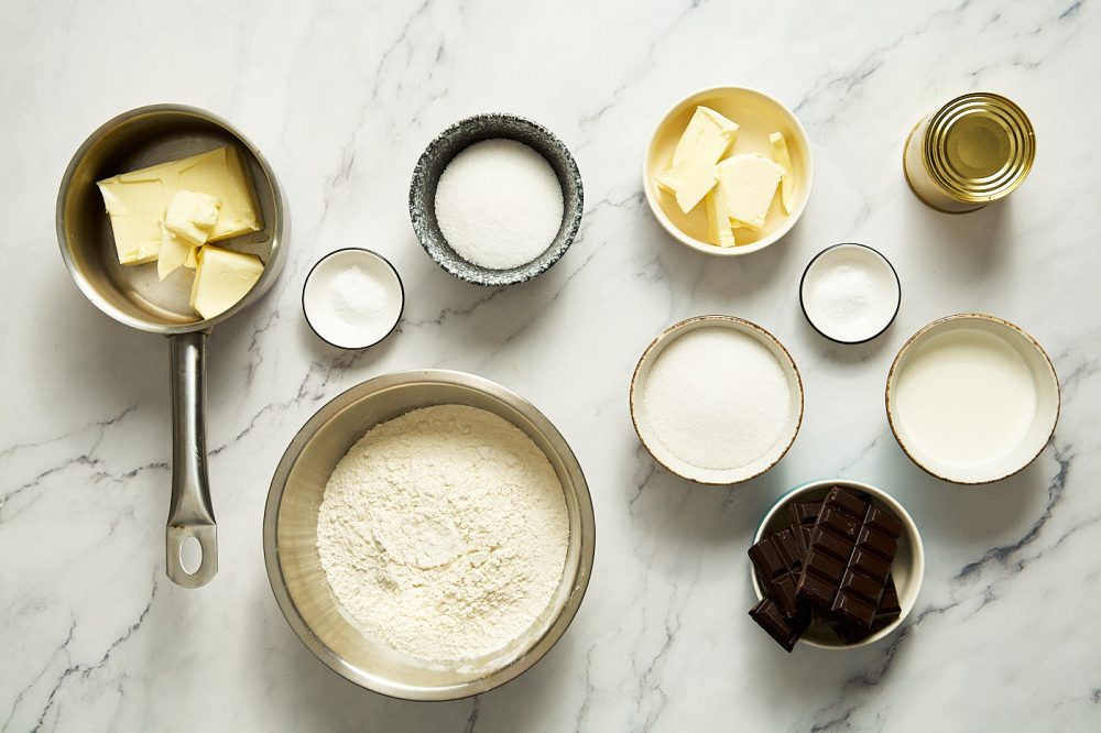 Ingredients needed to make homemade Twix: flour, sugar, salt, butter, condensed milk, cream, corn syrup, dark chocolate