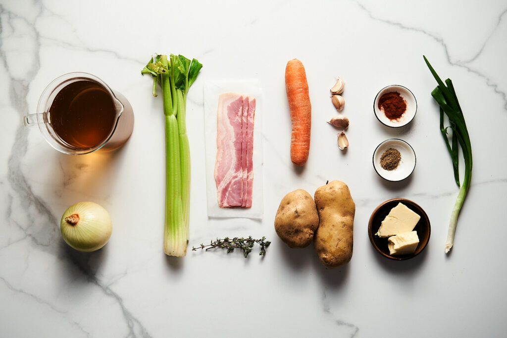 Інгредієнти необхідні для приготування Корисного картопляного супу: цибуля, морква, селера, картопля, бульйон, часник, паприка, коріандр, чебрець, чеддер, бекон, зелена цибуля