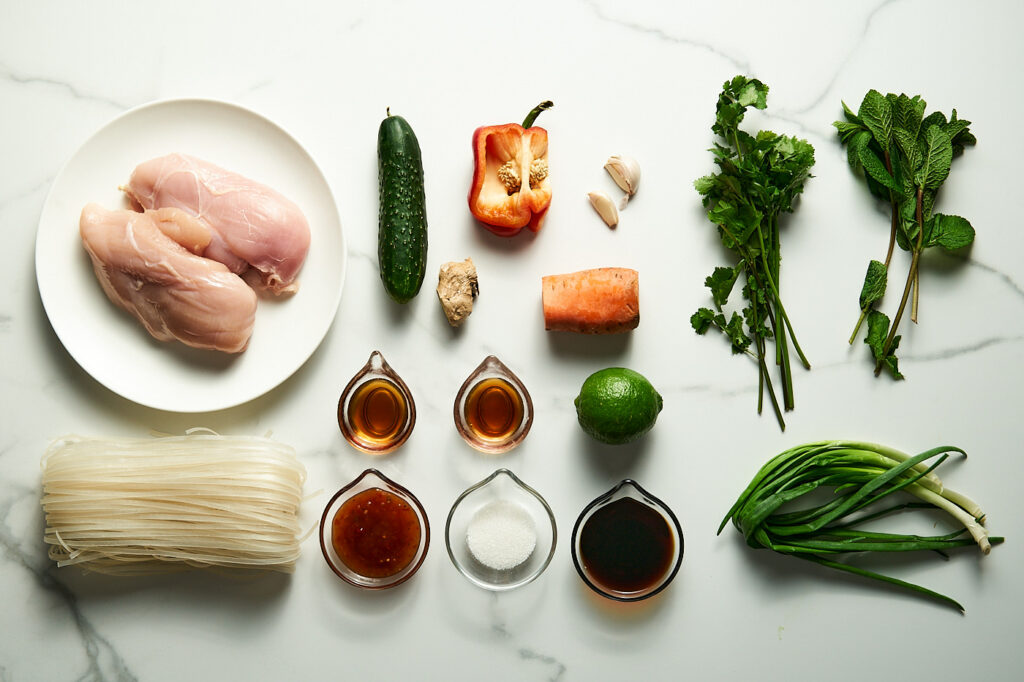Ingredients for Thai salad with chicken and noodles: chicken, noodles, cucumber, carrot, sweet pepper, green onion, cilantro, mint, cashews or peanuts, soy sauce, chili-sweet sauce, fish sauce, lime juice, garlic, sugar, ginger, sesame oil, ground chili.