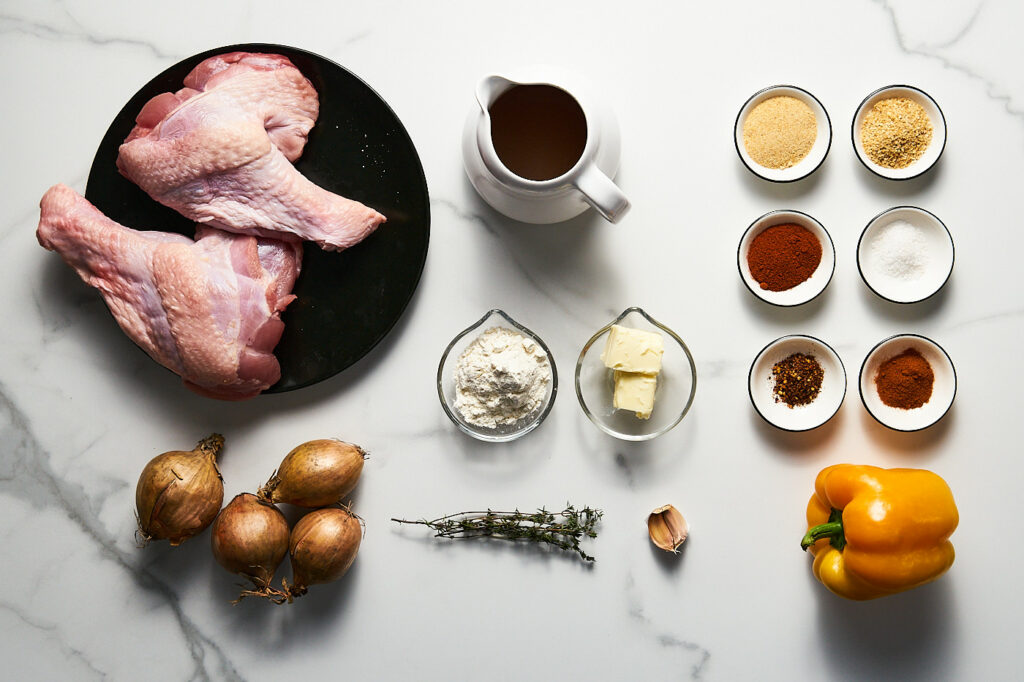 Ingredients needed to make braised and baked turkey wings in gravy: onion, sweet pepper, onion and garlic powder, salt, roasted chili powder, paprika, pepper, thyme, odive oil, butter, flour, chicken broth, garlic