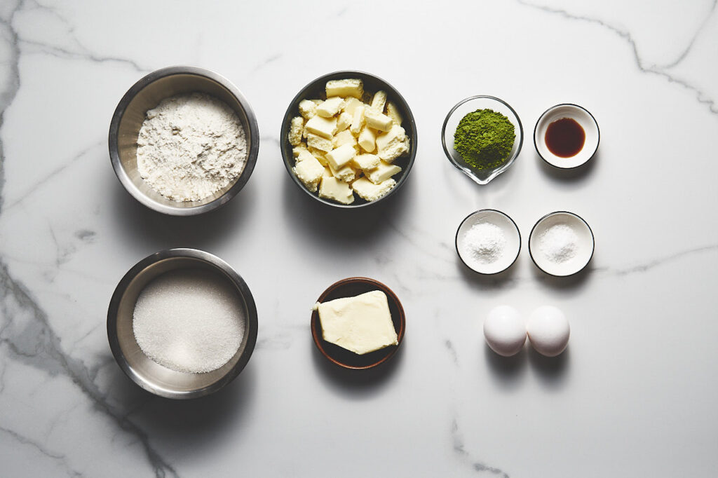 Ingredients needed to make Matcha Brownies: flour, matcha powder, sugar, white chocolate, butter, eggs, baking powder, vanilla extract, salt
