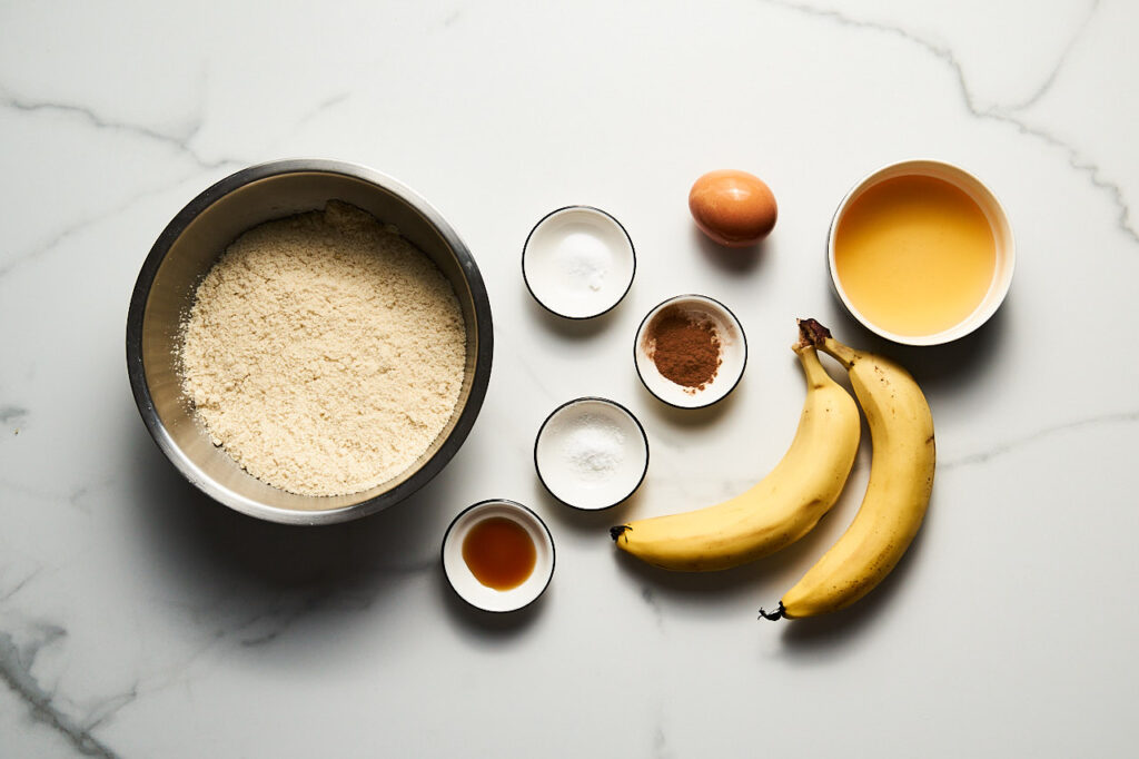 Інгредієнти, необхідні для приготування Бананового печива: банан, мигдальне борошно, мед, яйце, ванільний екстракт, сода, кориця, сіль