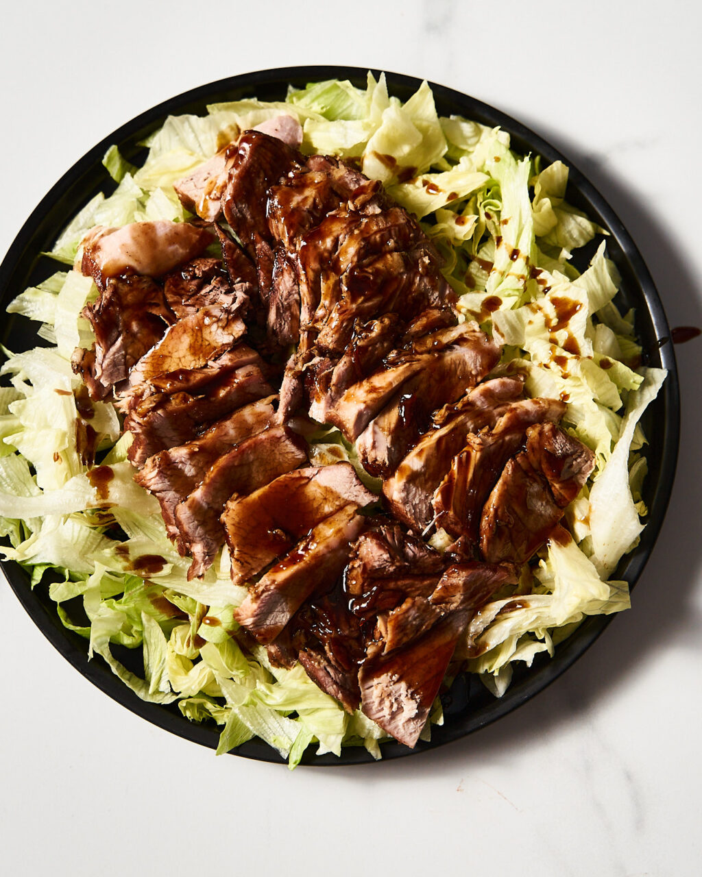 Chinese-style pork stewed in soy sauce on a plate with iceberg lettuce