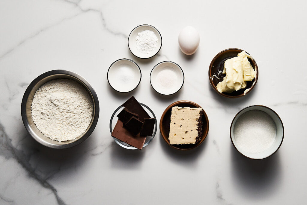 Ингредиенты необходимые для приготовления Печенья с шоколадом, халвой и коричневым маслом: шоколад, сливочное масло, сахар, яйцо, халва, сода, разрыхлитель, соль